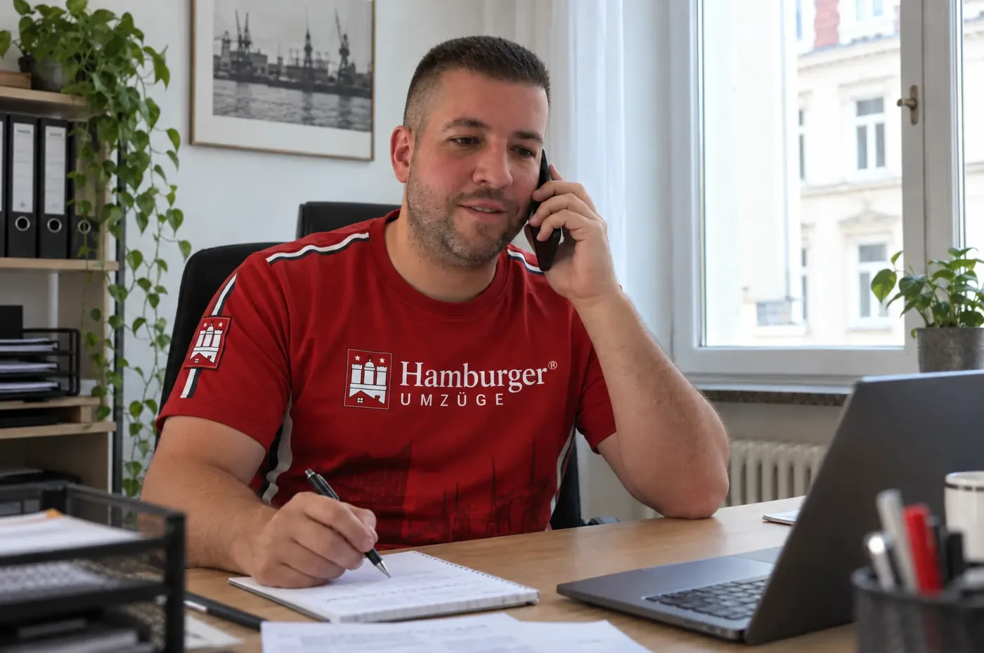 Marcel Lewinski von Hamburger Umzüge nimmt telefonisch Umzugsdetails auf und notiert sie am Schreibtisch